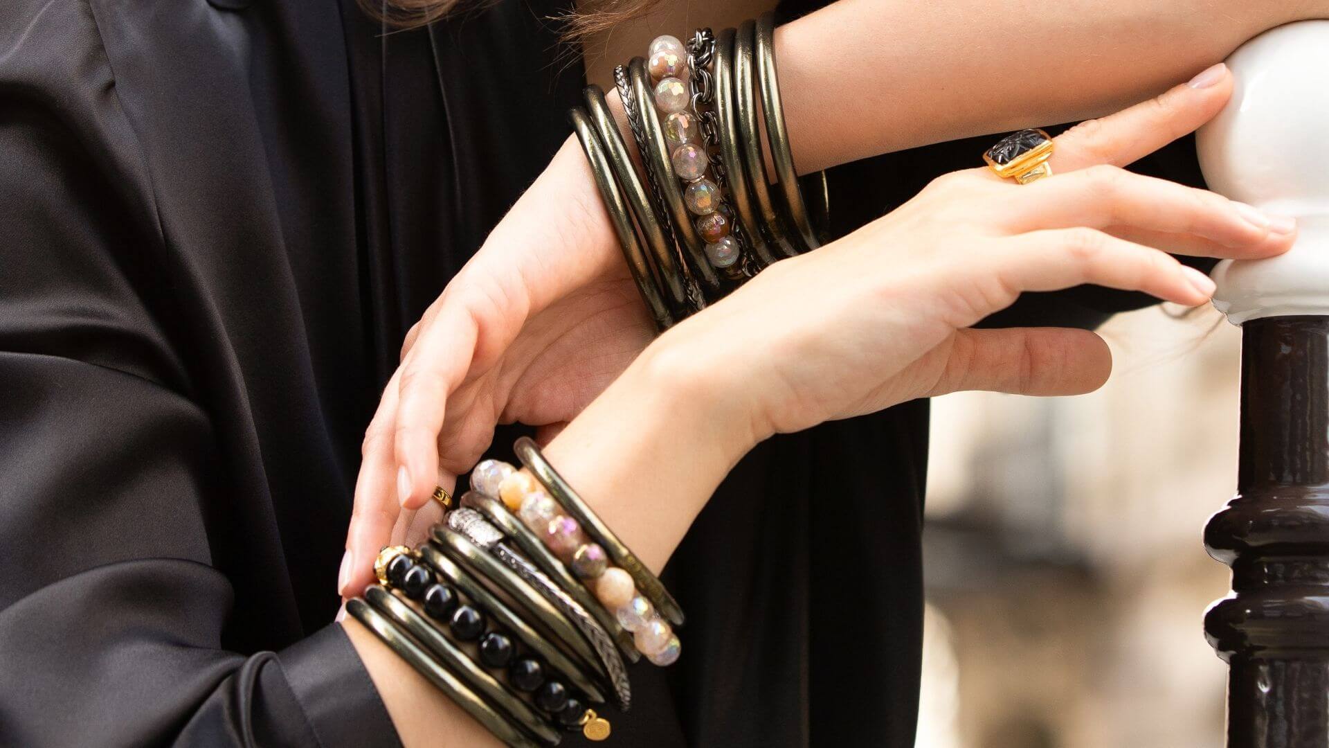 A woman wearing multiple bracelets and a gold ring on her wrist.